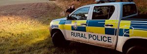 A police car in a field with an officer looking out with binoculars